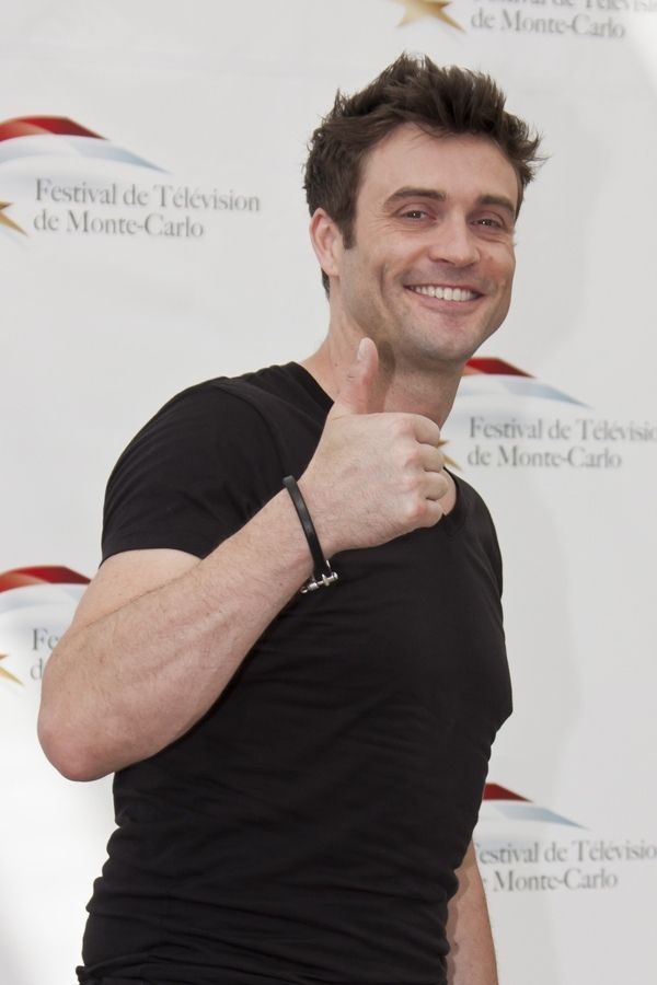 A man in a black t-shirt giving a thumbs-up gesture.