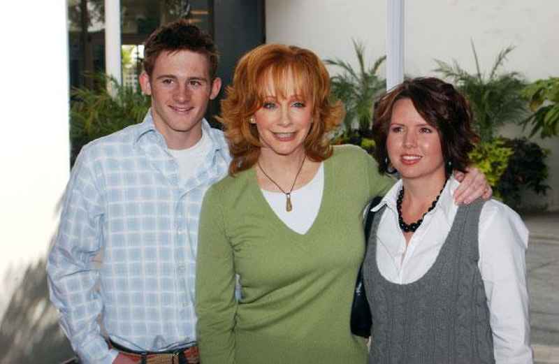 A man, a woman in a green sweater, and another woman posing together
