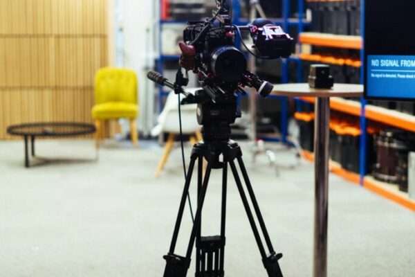A professional video camera on a tripod in a studio