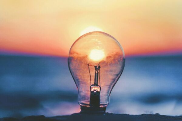 A glowing lightbulb on a beach at sunset.