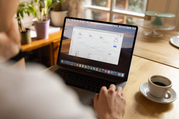 A person using a laptop on a wooden desk, showing a data dashboard.