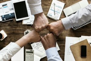 Four people putting their fists together over a desk.