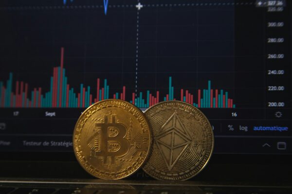 Physical Bitcoin and Ethereum coins placed over a financial trading chart.