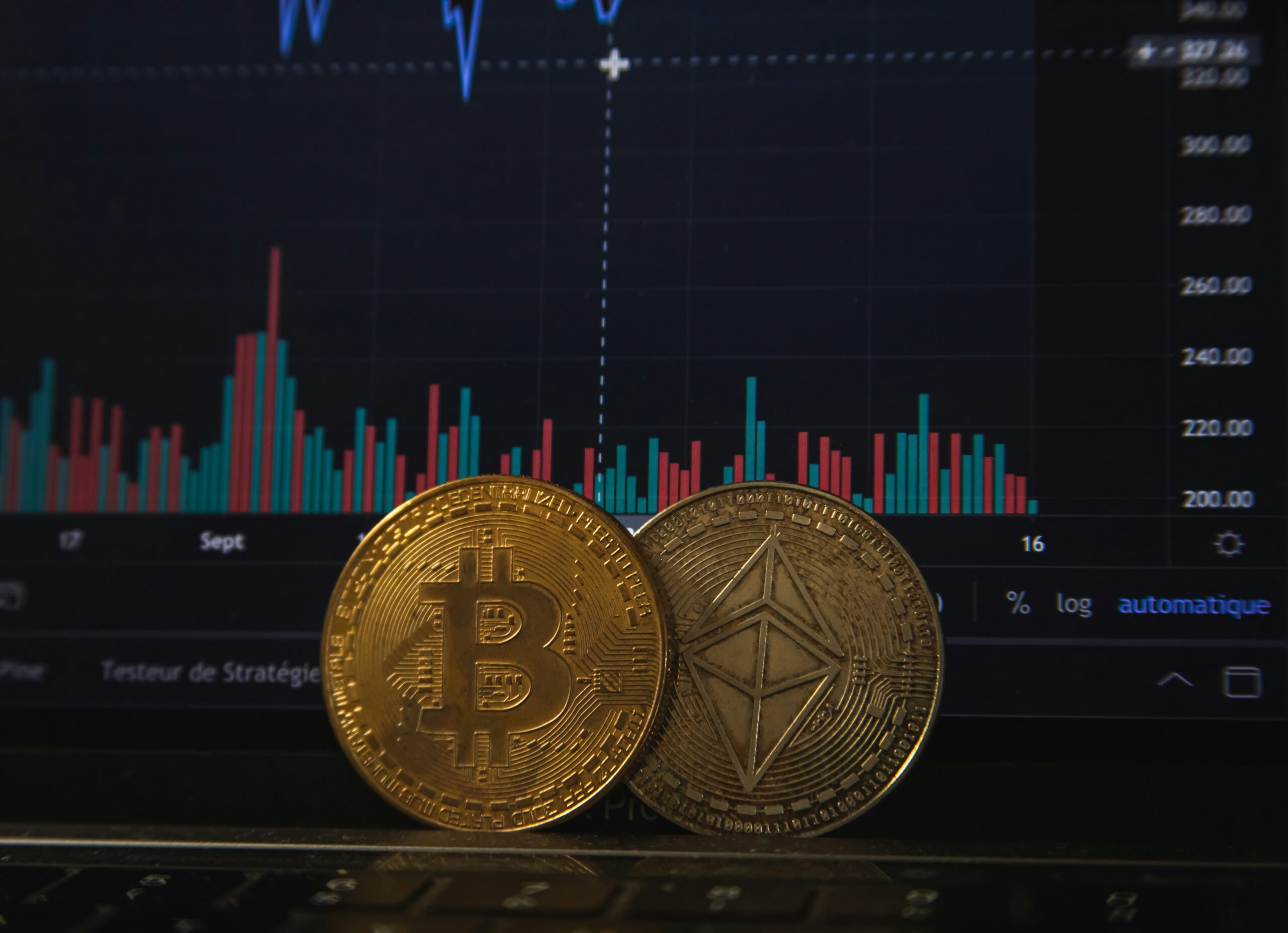 Physical Bitcoin and Ethereum coins placed over a financial trading chart.