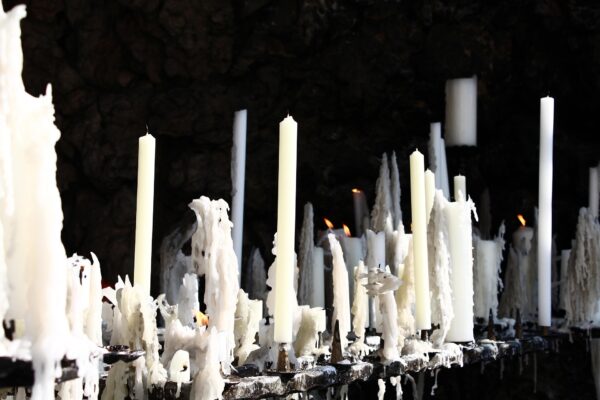 Multiple white candles of different heights burning together.