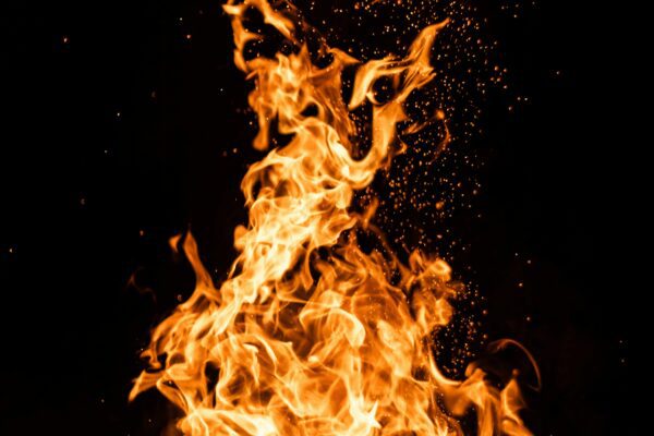 A bright, intense orange fire flame against a solid black background.