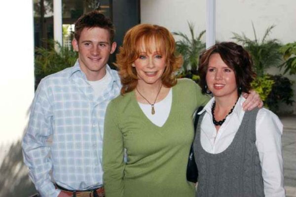 A man, a woman in a green sweater, and another woman posing together