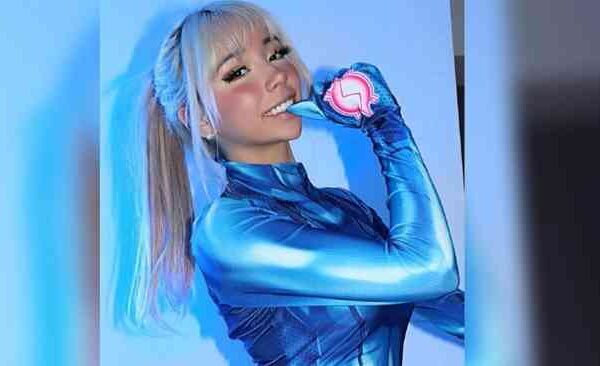 A woman posing in a shiny blue futuristic outfit