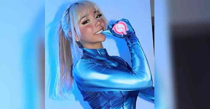 A woman posing in a shiny blue futuristic outfit