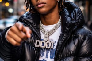 A young man in a puffer jacket wearing a large silver chain.