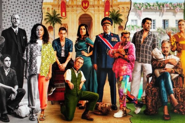 A group of actors in colorful costumes posing for a film poster.
