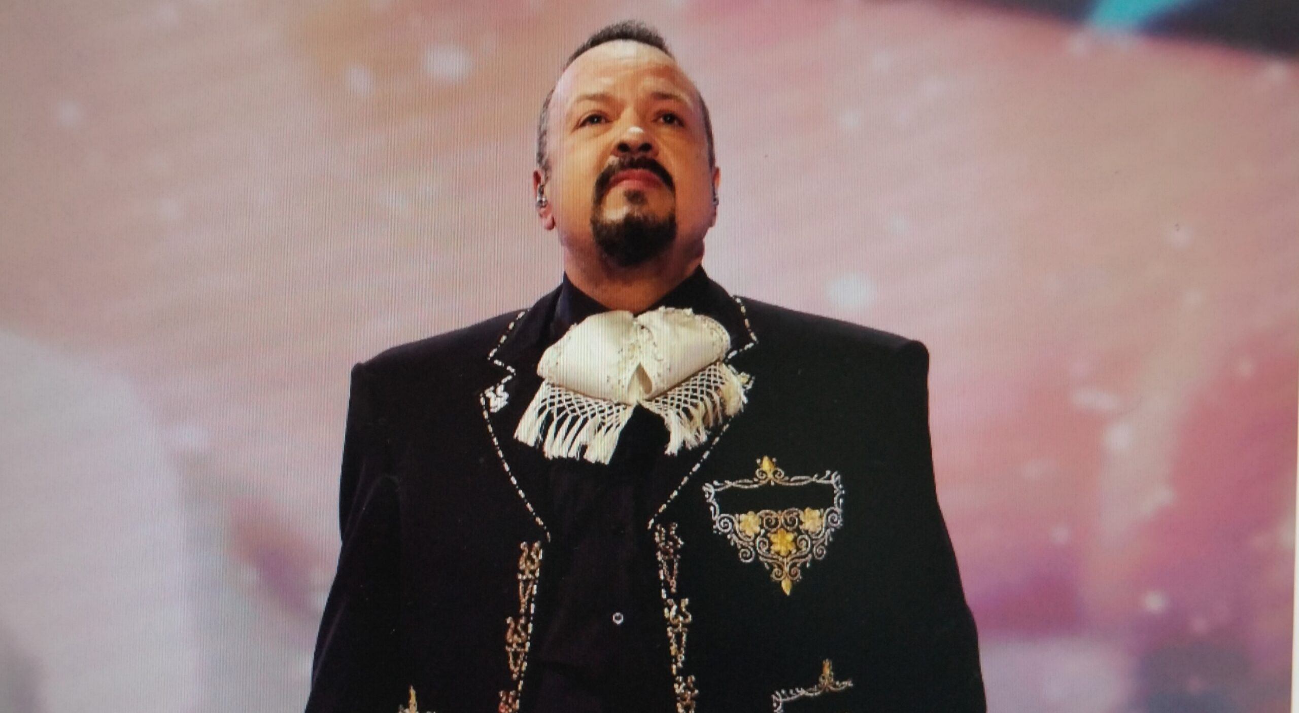 A man in a traditional decorative black suit performing.