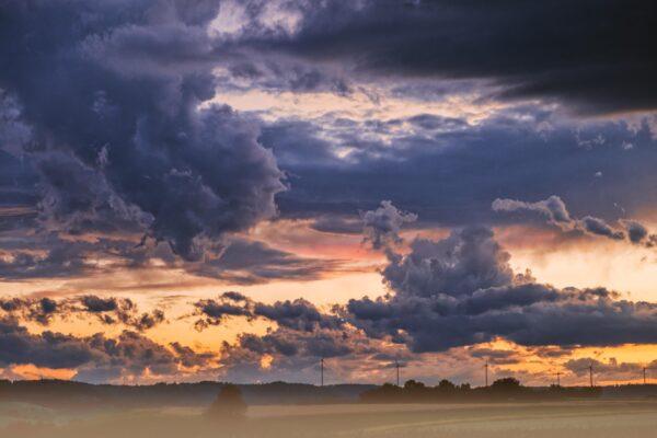 A dramatic sky with orange and blue clouds over a flat horizon.