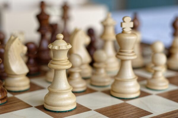 A close-up of wooden chess pieces (King and Queen) on a chessboard.