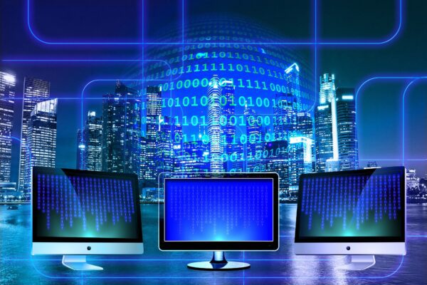 Multiple monitors displaying a glowing blue digital city skyline.