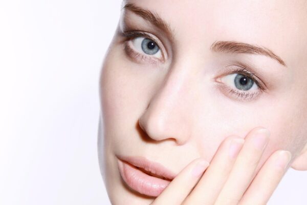A close-up of a woman’s face with her hand touching her cheek, representing beauty or skincare.
